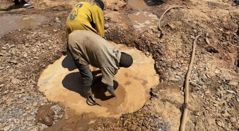 Deux enfants lavent de la terre aurifère dans une mare peu profonde
