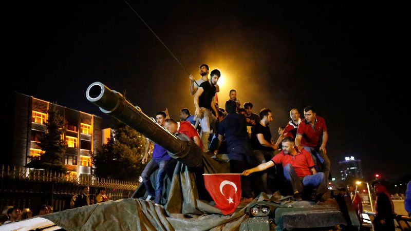 people stand on a turkish army tank in ankara